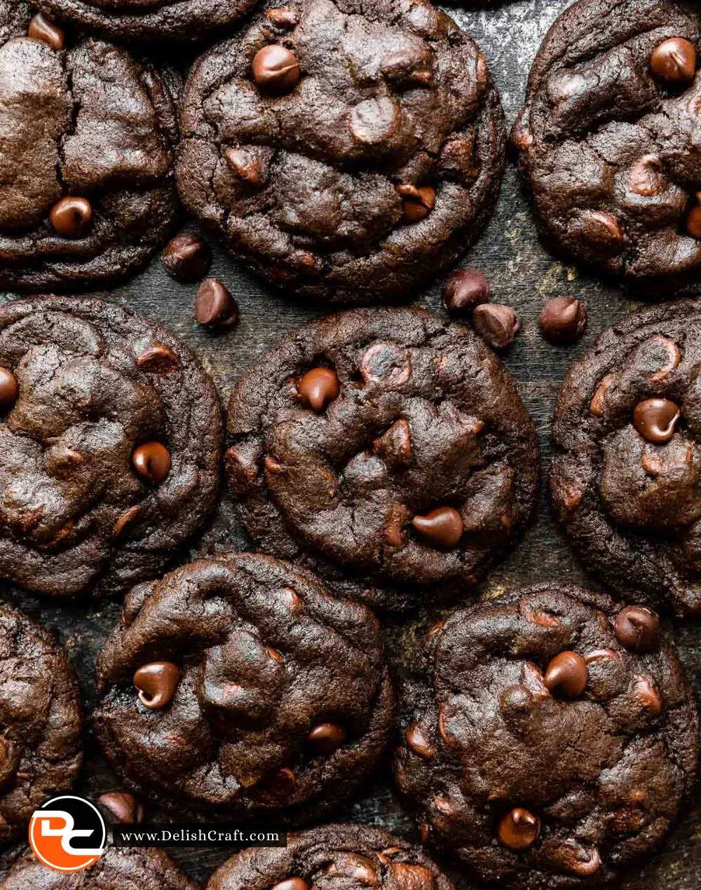 Double chocolate chip cookies stacked on a plate with melting chocolate chips.