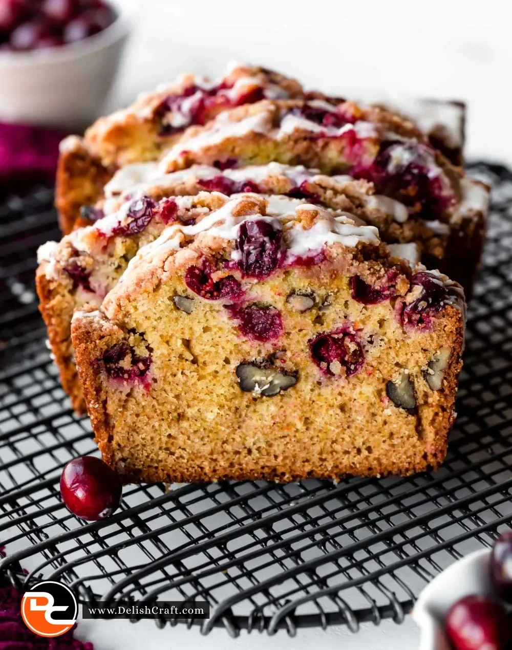 Sliced orange glazed cranberry bread on a wooden table.