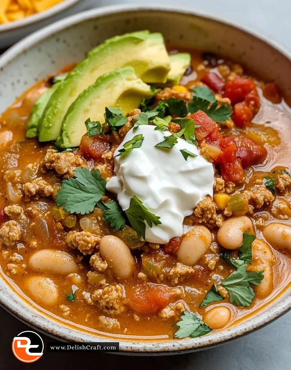 A bowl of Turkey White Bean Chili topped with fresh herbs and served with cornbread.