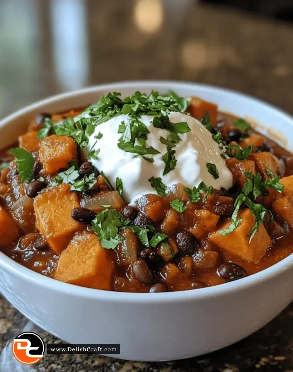 Bowl of sweet potato black bean chili topped with cilantro and served with bread