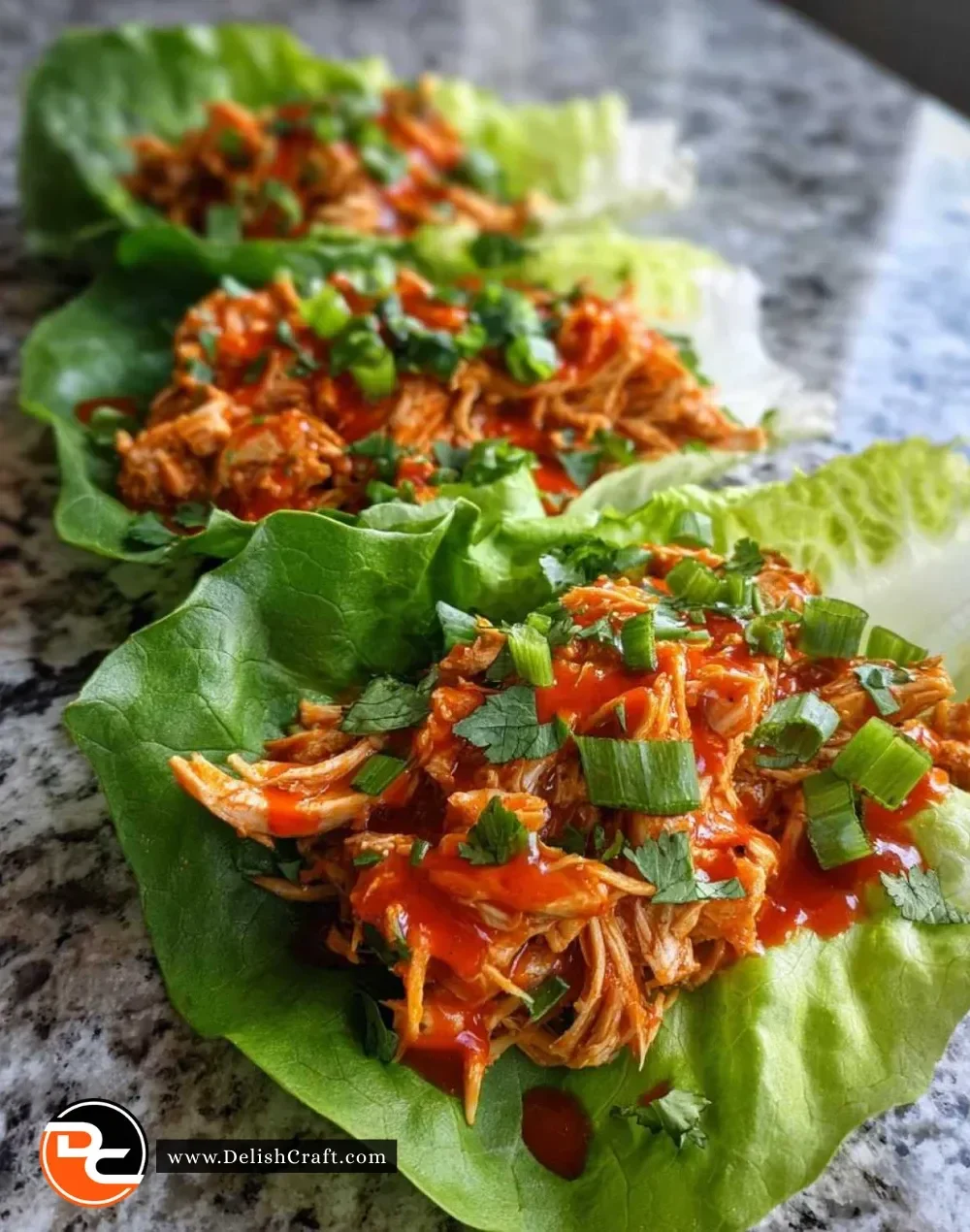 Spicy Buffalo Chicken Lettuce Wraps served on a plate garnished with veggies.