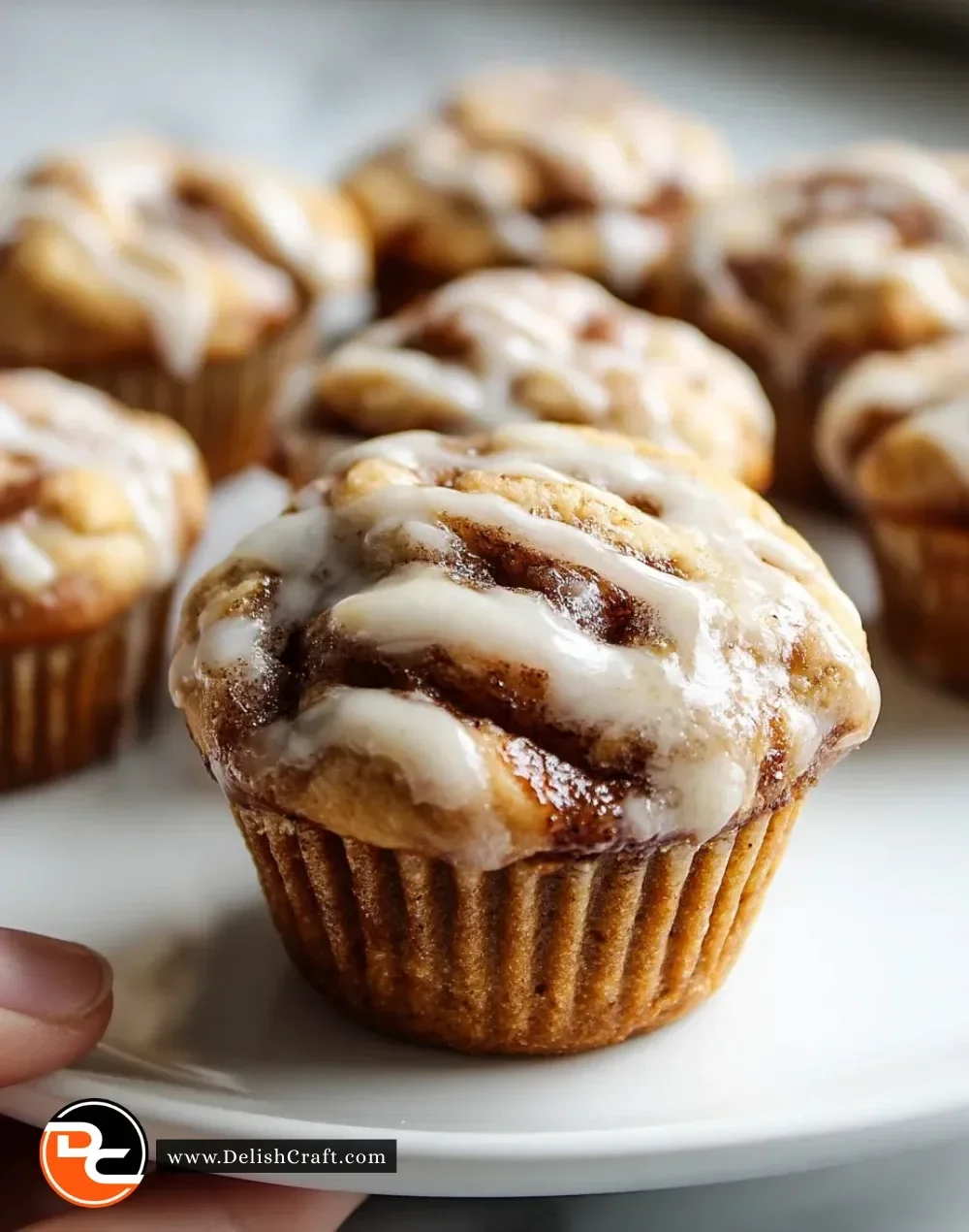 Freshly baked cinnamon roll muffins drizzled with icing and topped with cinnamon.