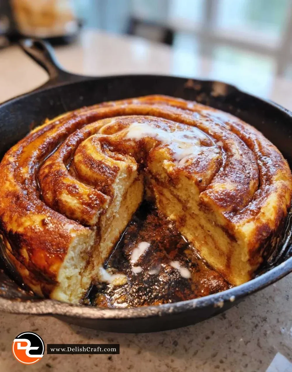 Cinnamon roll pancake skillet topped with icing and garnished with cinnamon.