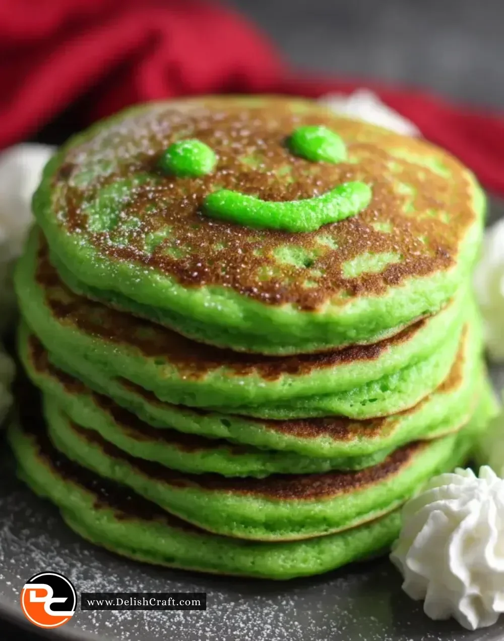Stack of vibrant Grinch Pancakes topped with whipped cream and festive decorations.