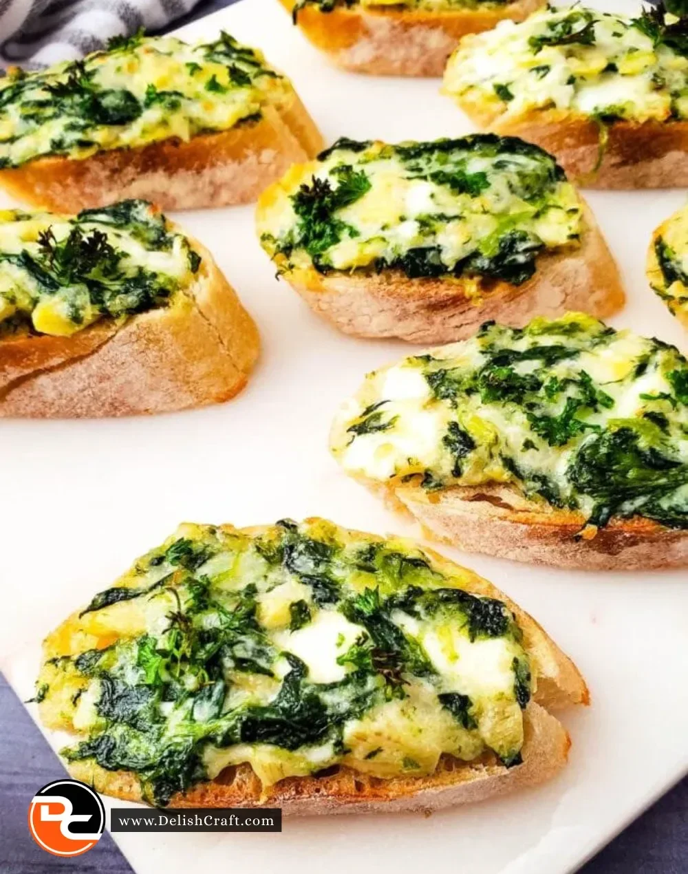 Spinach Artichoke Crostini topped with cheese and herbs