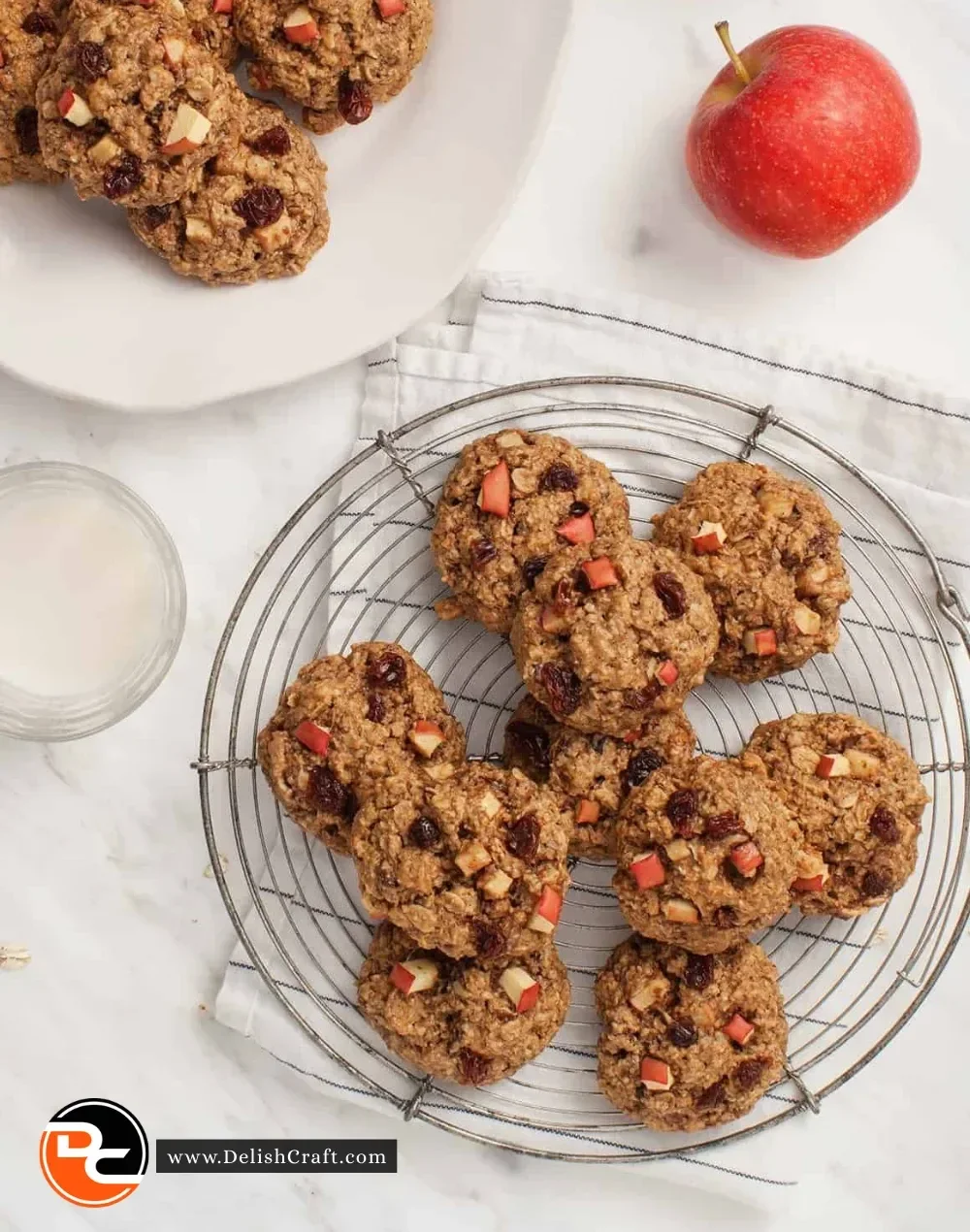 Baked apple oatmeal cookies on a cooling rack with a sprinkle of cinnamon.