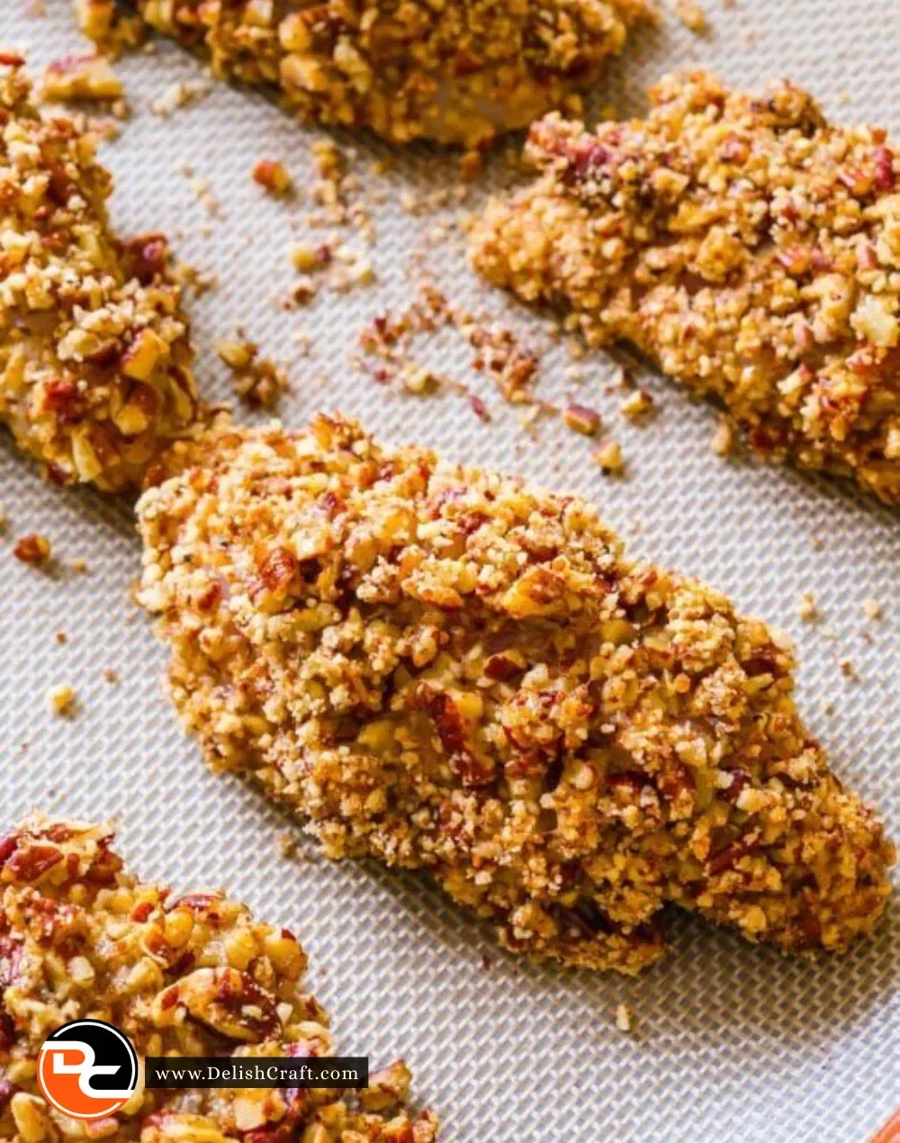 Baked Pecan Crusted Chicken Fingers on a plate, garnished with fresh herbs