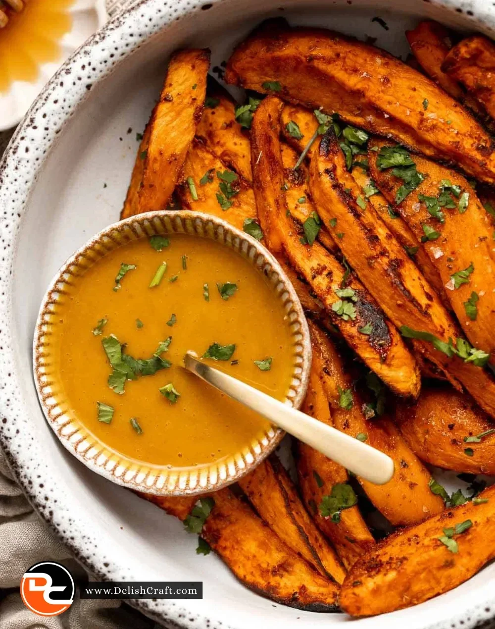 Baked sweet potato wedges served on a plate, garnished with herbs.