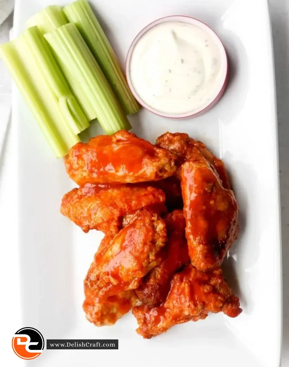 Plate of spicy Buffalo hot wings garnished with celery and dipping sauce