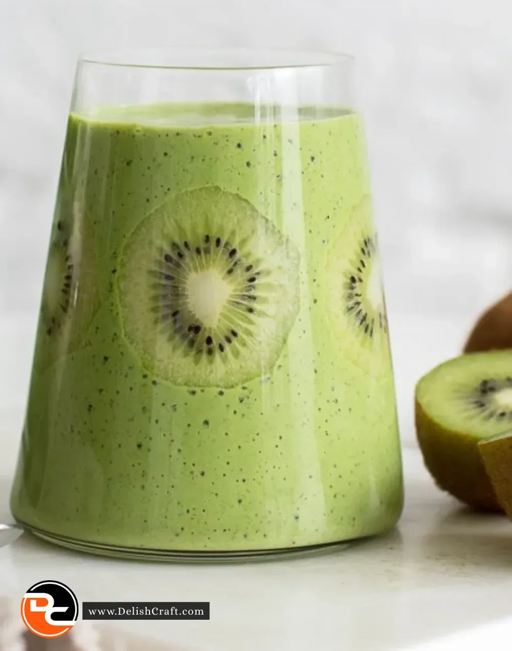 Green spinach kiwi smoothie in a glass with fresh ingredients around it
