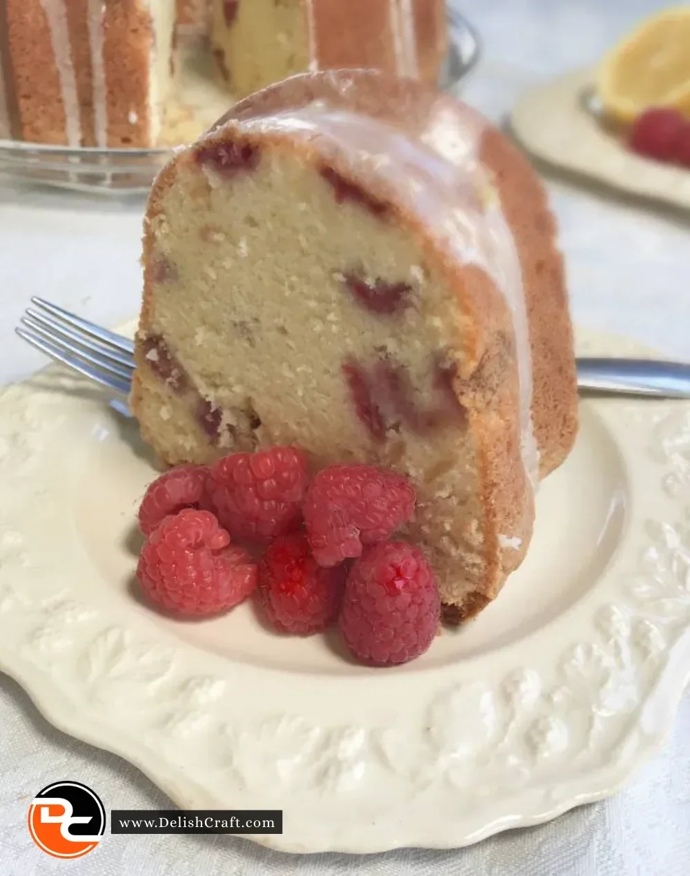 Lemon raspberry pound cake slices on a plate with fresh raspberries and lemon zest.