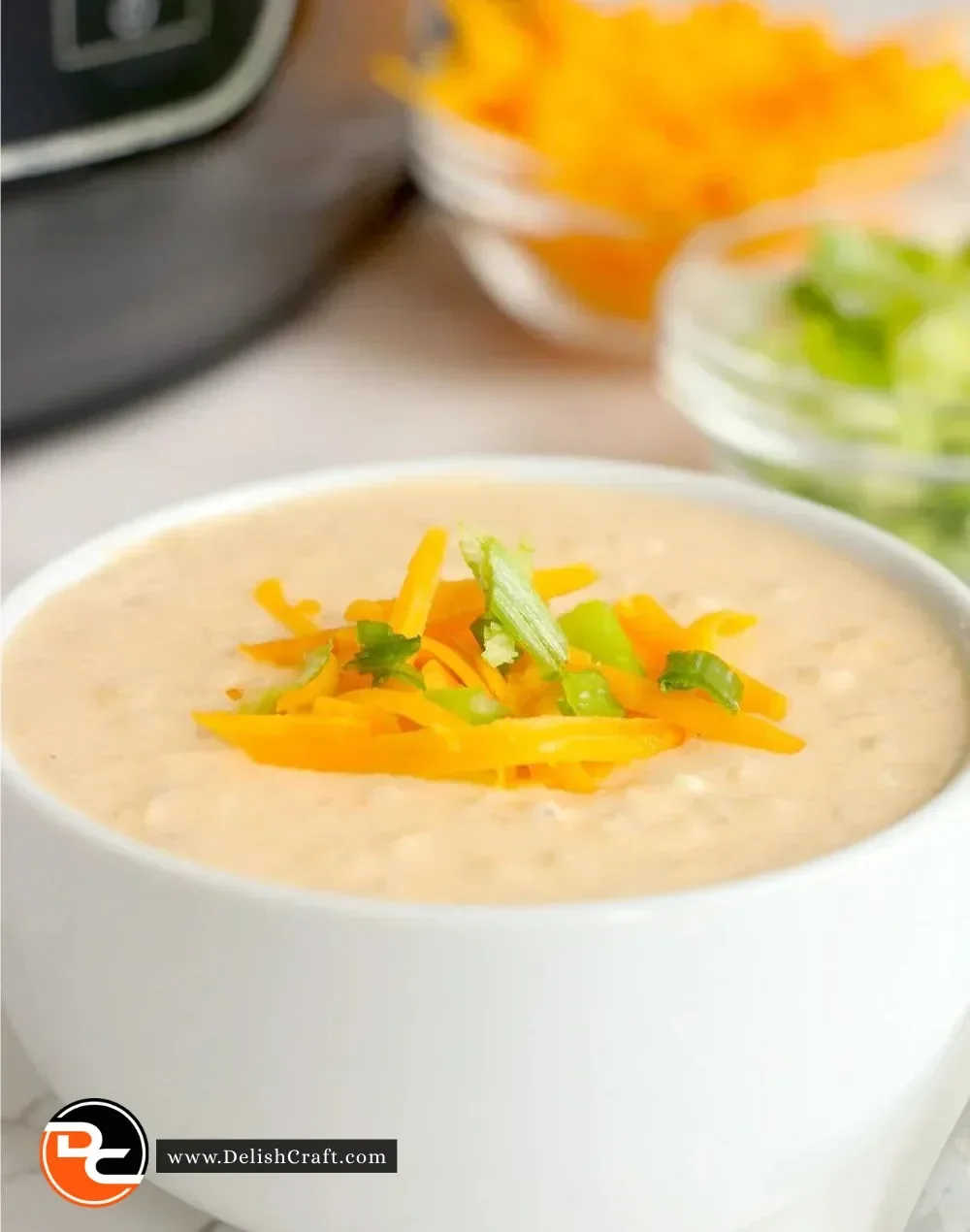 Bowl of Ninja Foodi cheesy cauliflower soup topped with cheese and herbs