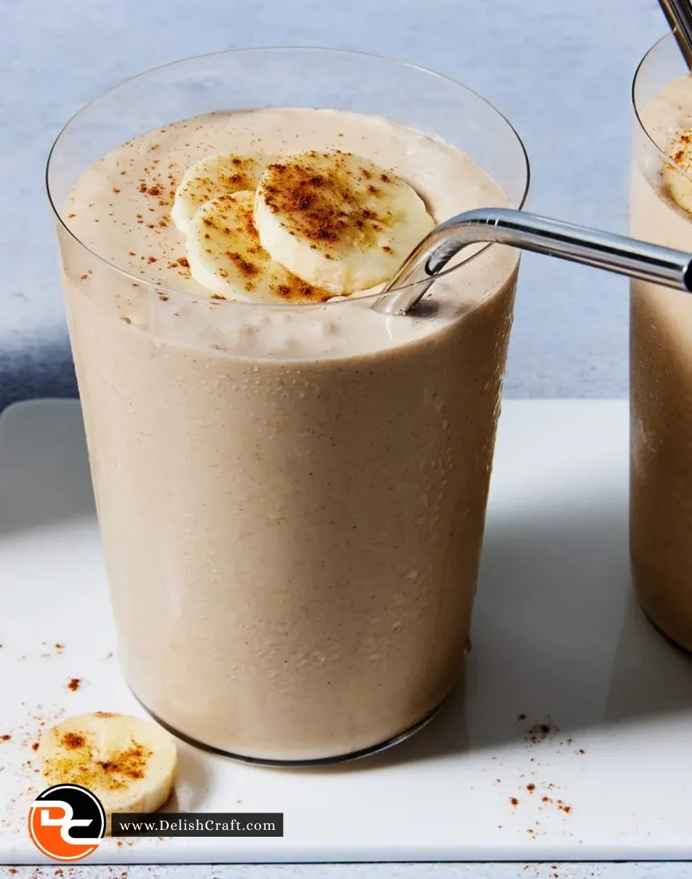 Peanut Butter Banana Smoothie in a glass with a banana and peanut butter on the side