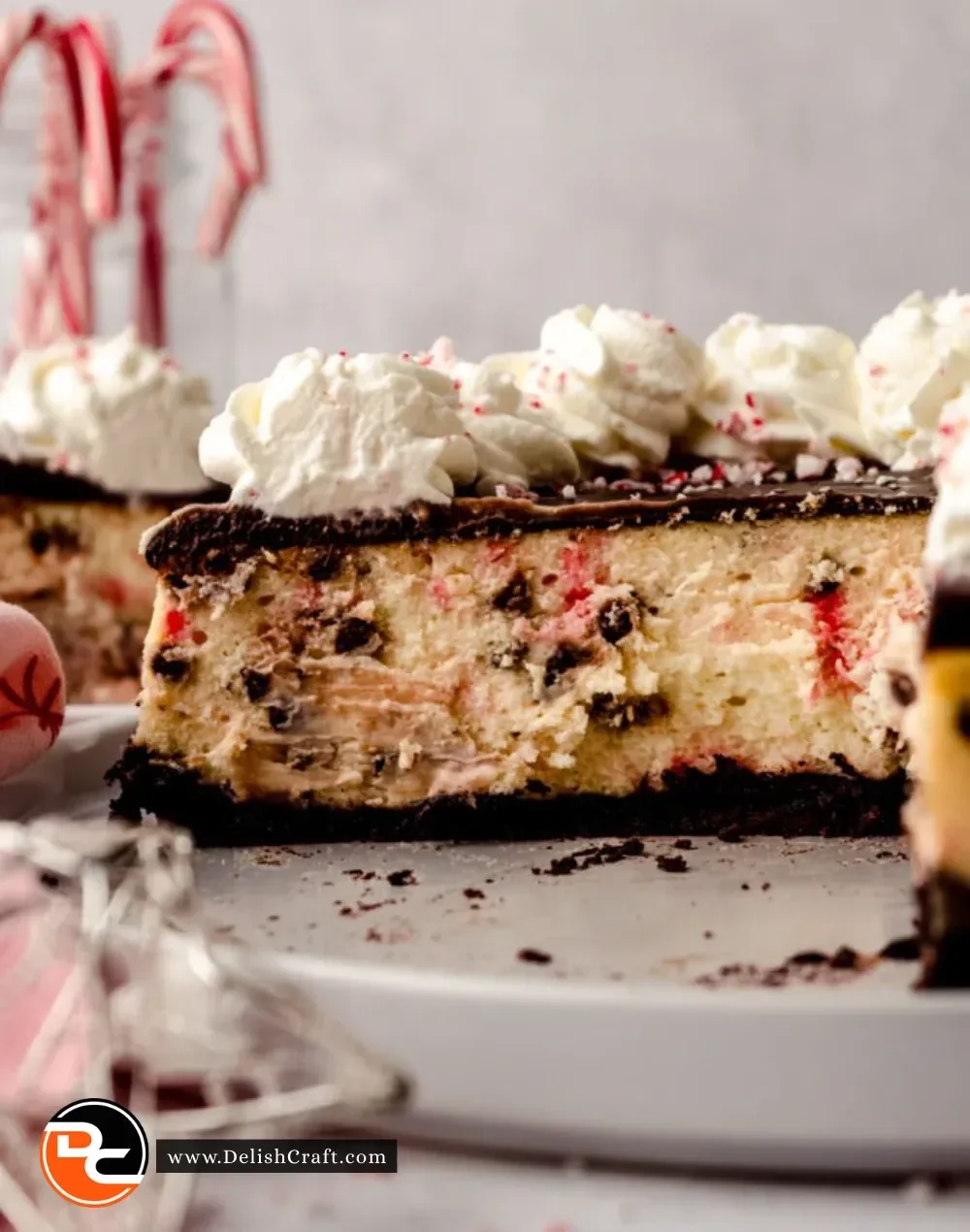 Slice of Peppermint Bark Cheesecake topped with chocolate and peppermint candy.