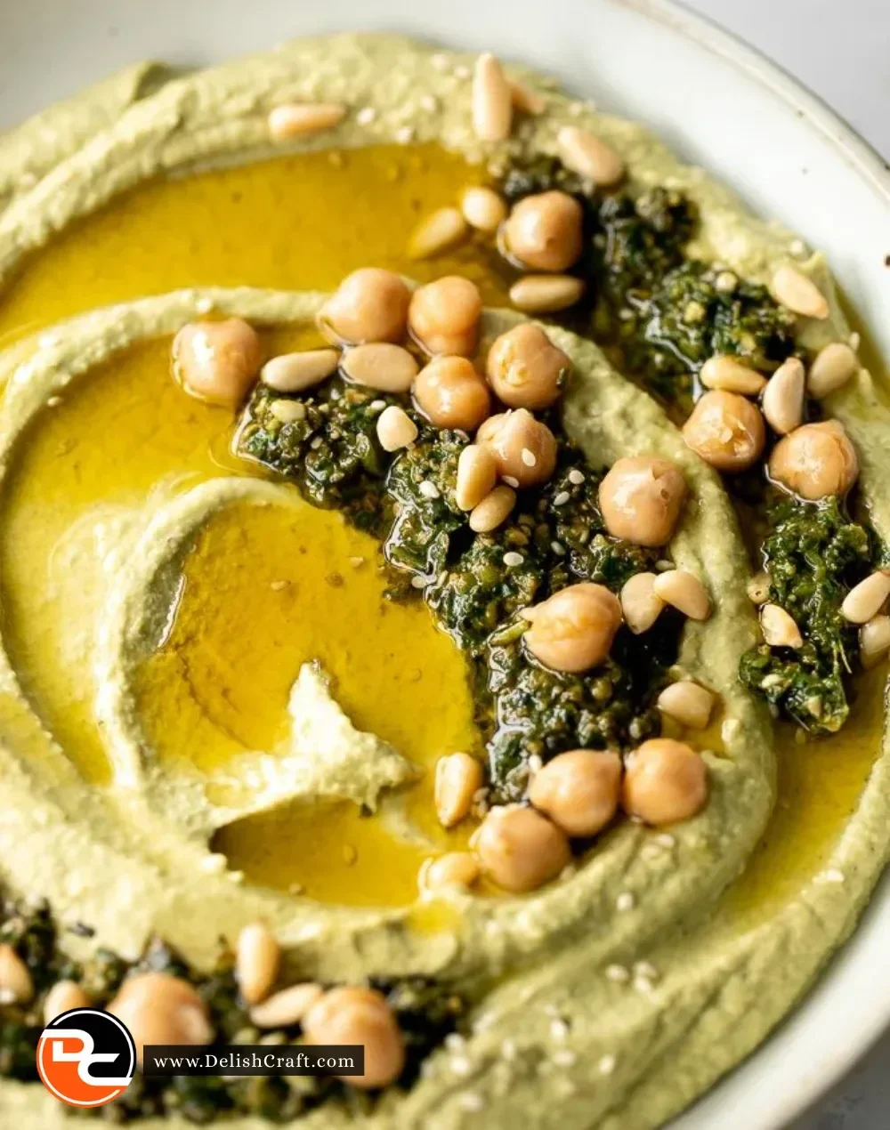 Bowl of vibrant green pesto hummus served with fresh vegetables