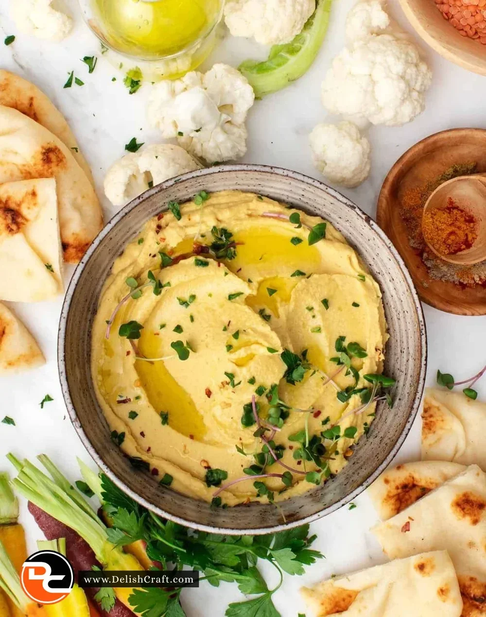 Bowl of creamy red lentil hummus served with pita and vegetables