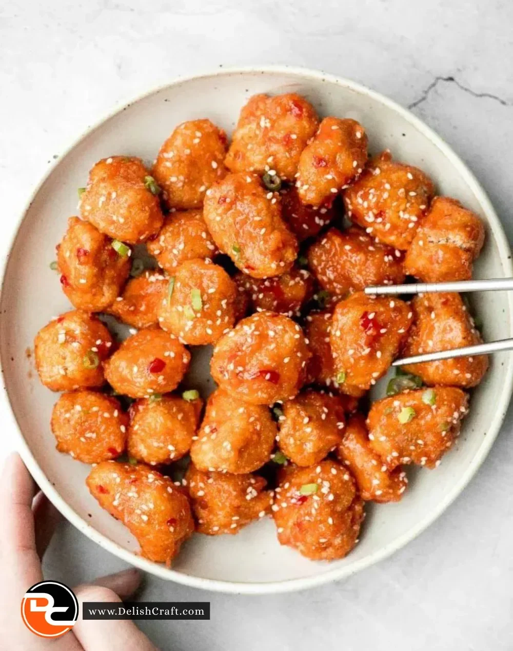 Plate of delicious Sweet Chili Chicken Bites garnished with fresh herbs.