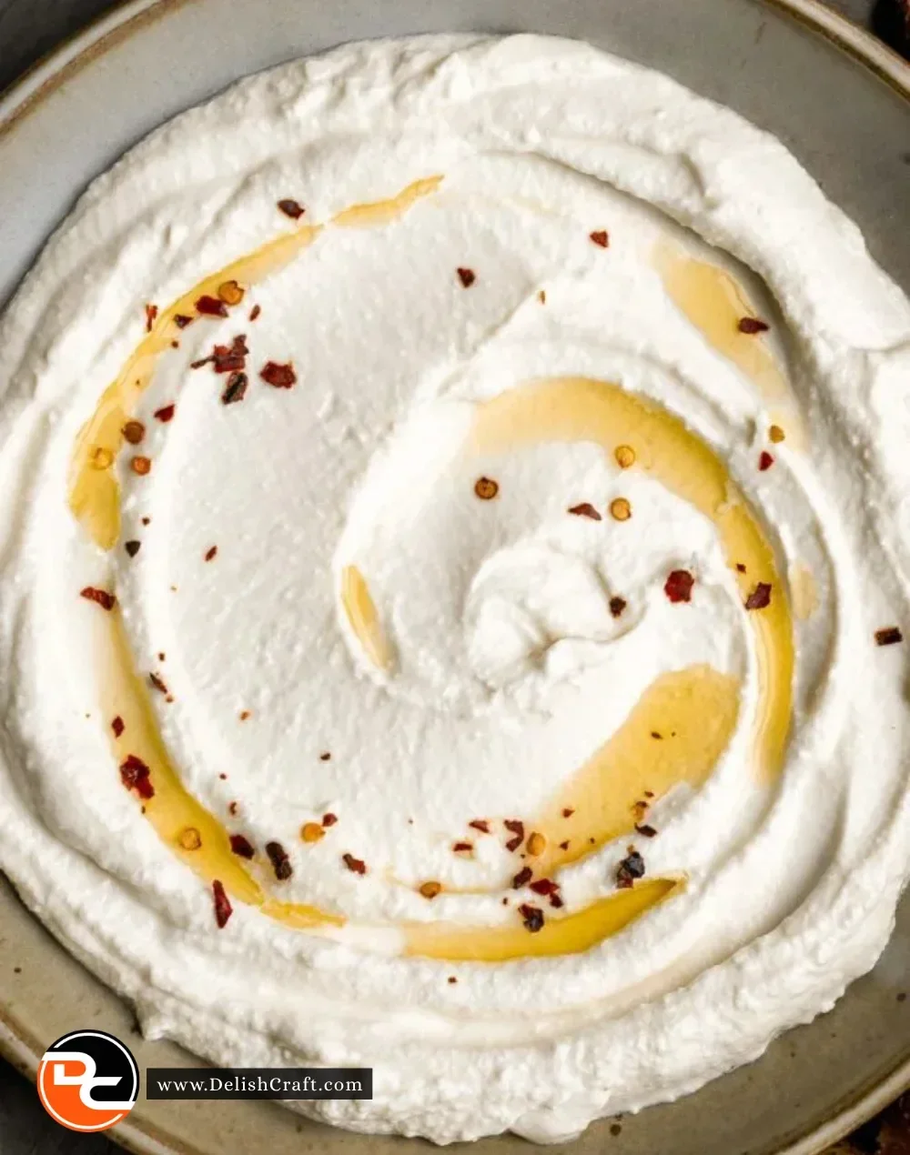 A bowl of creamy whipped feta surrounded by fresh vegetables and pita bread.