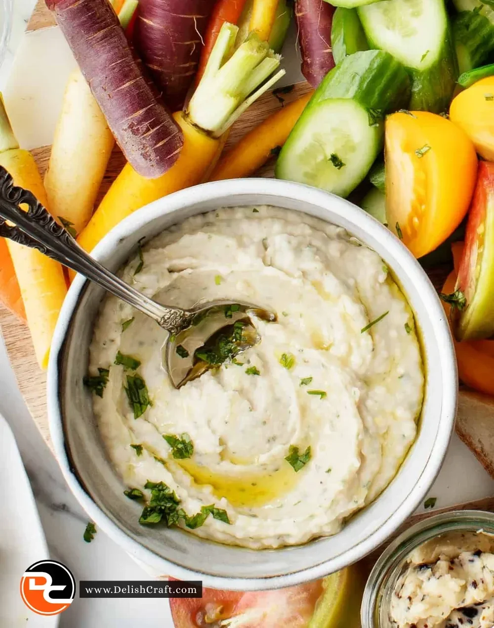 Creamy white bean dip served in a bowl with fresh vegetables on the side.