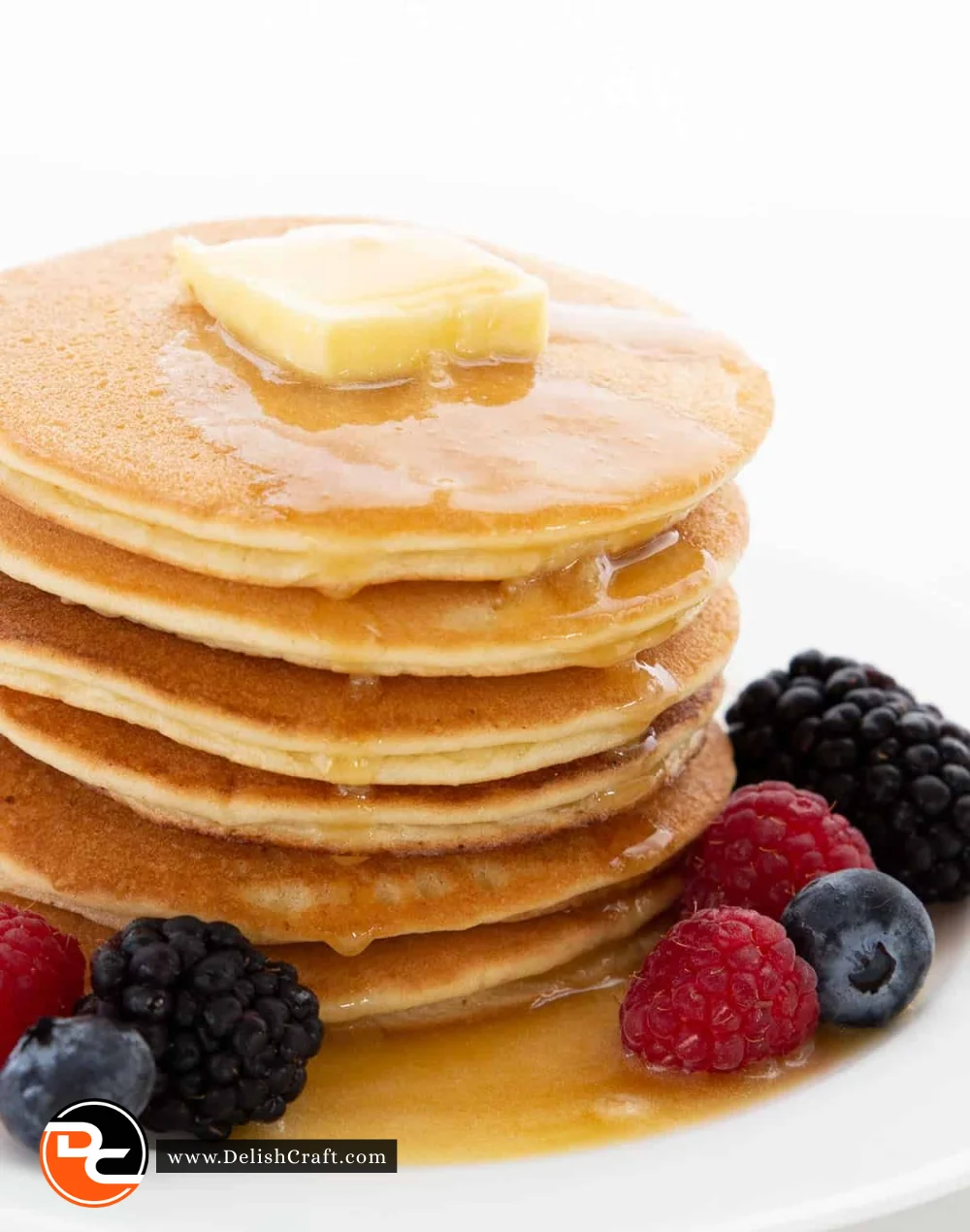 Fluffy almond flour keto pancakes stacked on a plate with berries and syrup.