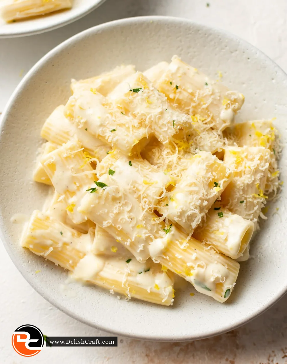 Bowl of creamy lemon pasta garnished with fresh herbs and lemon zest