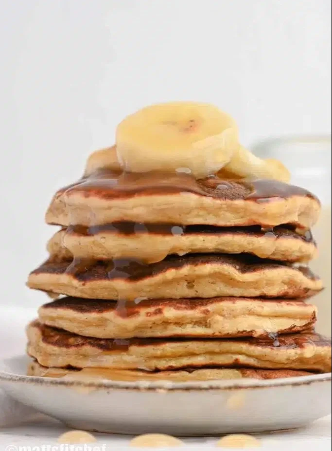 Fluffy banana protein pancakes topped with fresh bananas and syrup