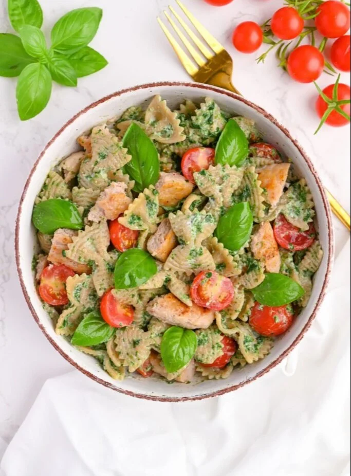 High protein pesto pasta dish with chicken garnished with basil
