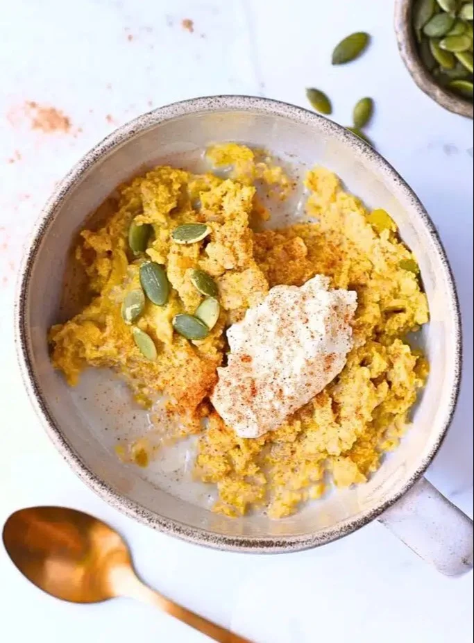 Bowl of high protein pumpkin oatmeal topped with nuts and spices