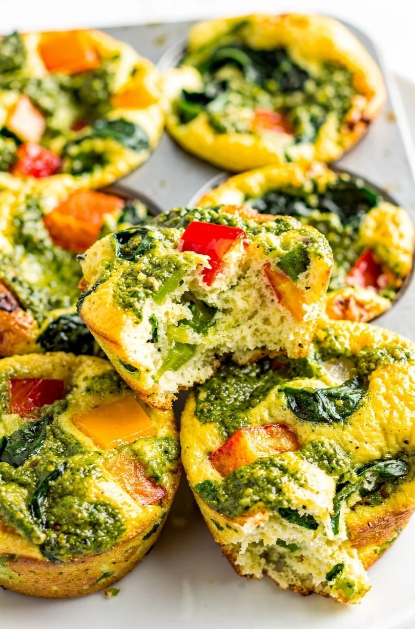 Pesto egg white bites served on a plate, garnished with fresh herbs.